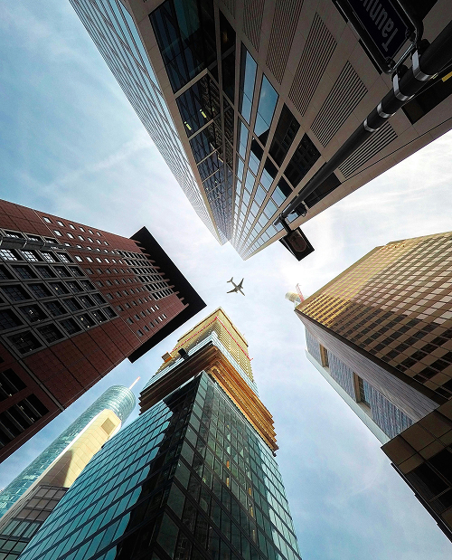 Blick in den Himmel auf ein Flugzeug hindurch durch die Hochhäuser in Frankfurt am Main